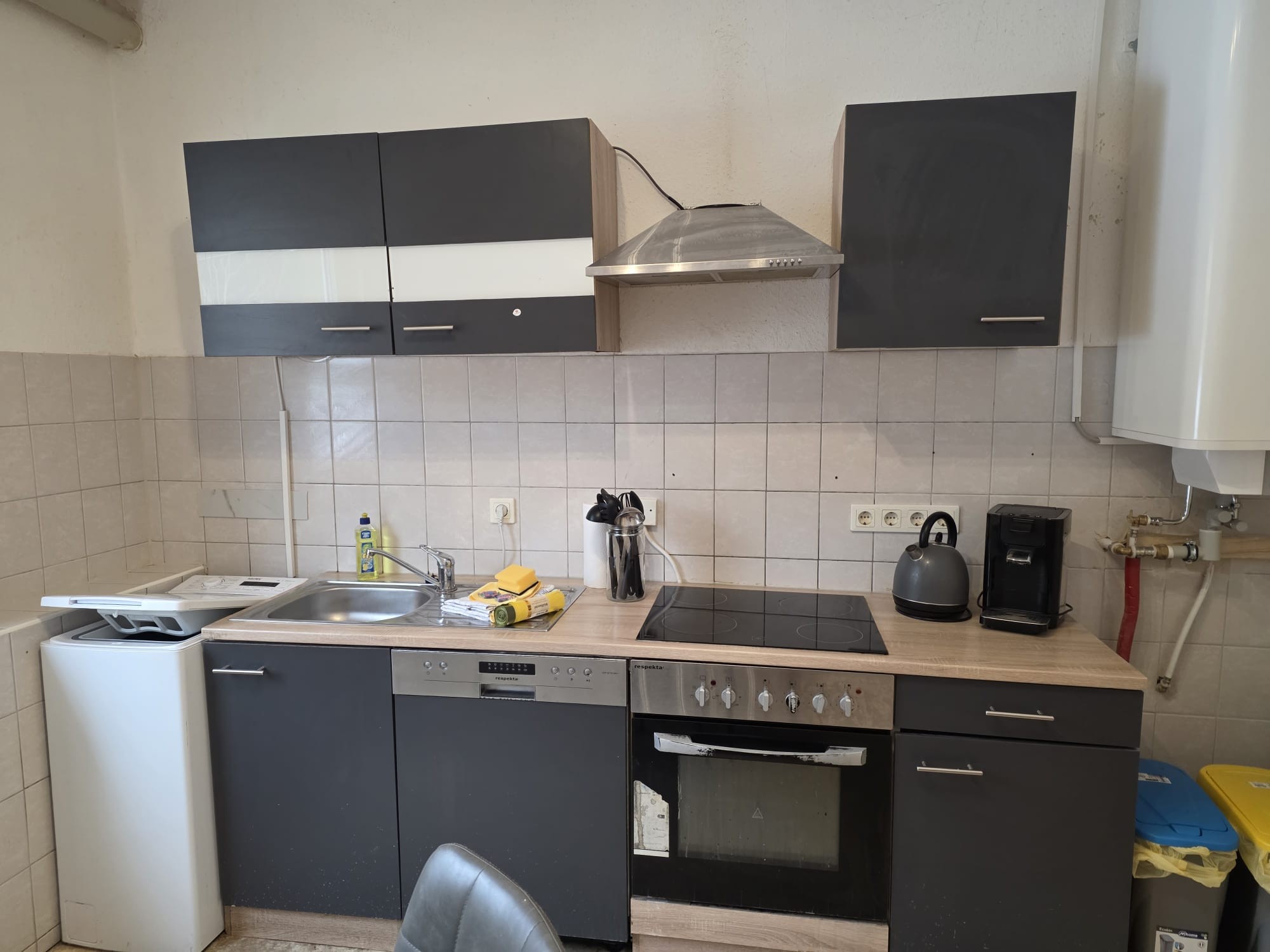 Küche mit Waschbecken, Ceran-Kochfeld, Backofen, Mikrowelle, Waschmaschine, Wäschetrockner, Tisch mit Stühlen, Kühl-Gefrierkombination